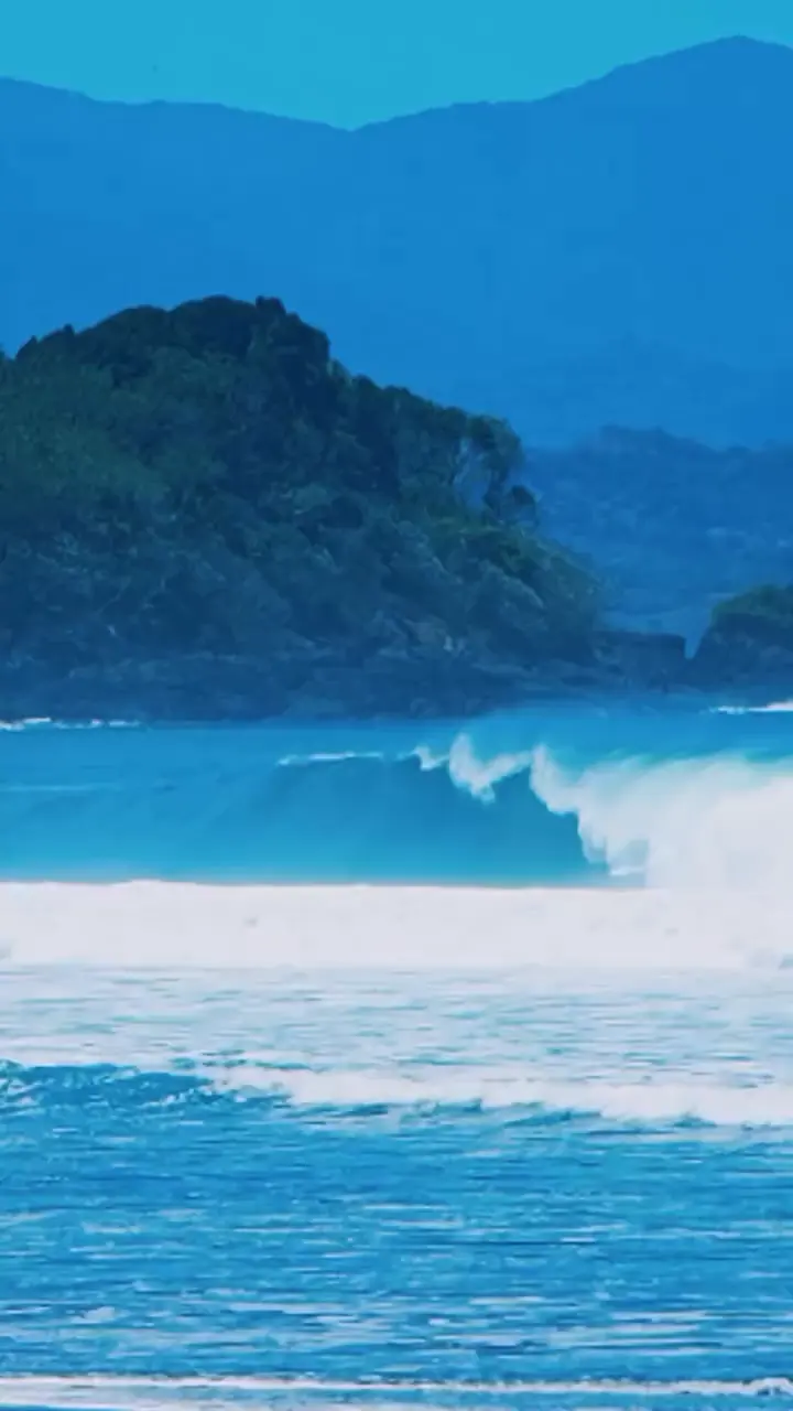 Olas rompiendo frente a una costa con cerros.